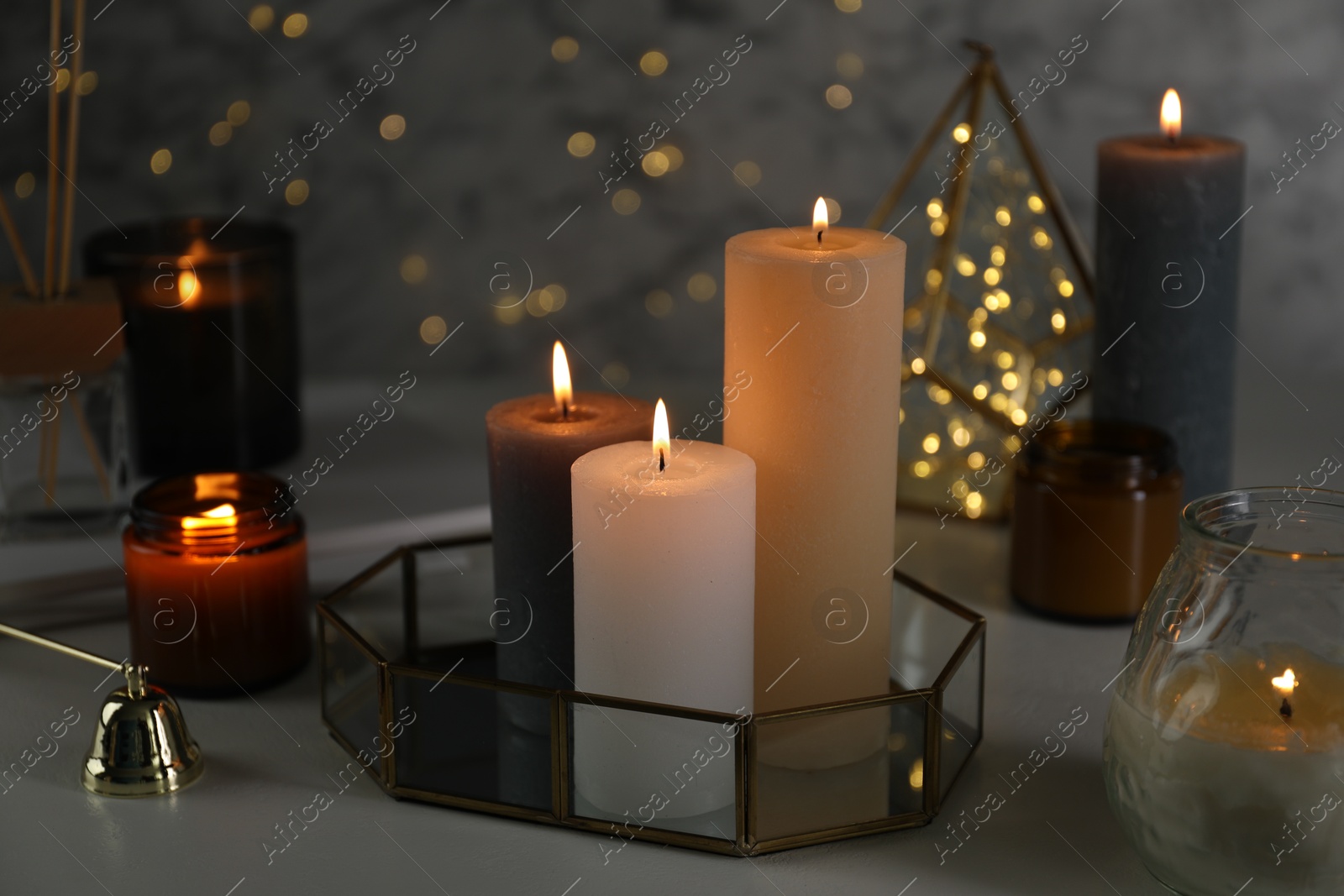 Photo of Beautiful burning candles on table against blurred lights, closeup