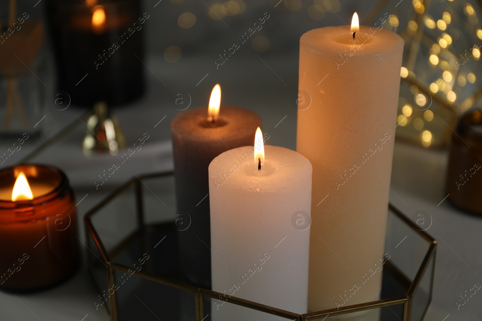 Photo of Beautiful burning candles on table against blurred lights, closeup