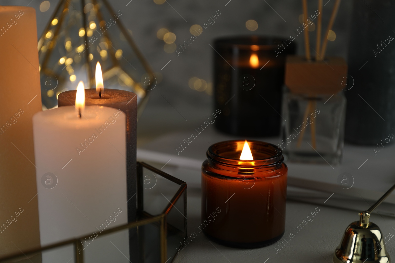 Photo of Beautiful burning candles on table against blurred lights, closeup