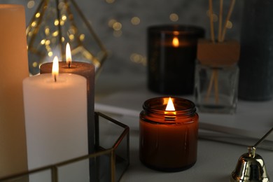 Photo of Beautiful burning candles on table against blurred lights, closeup