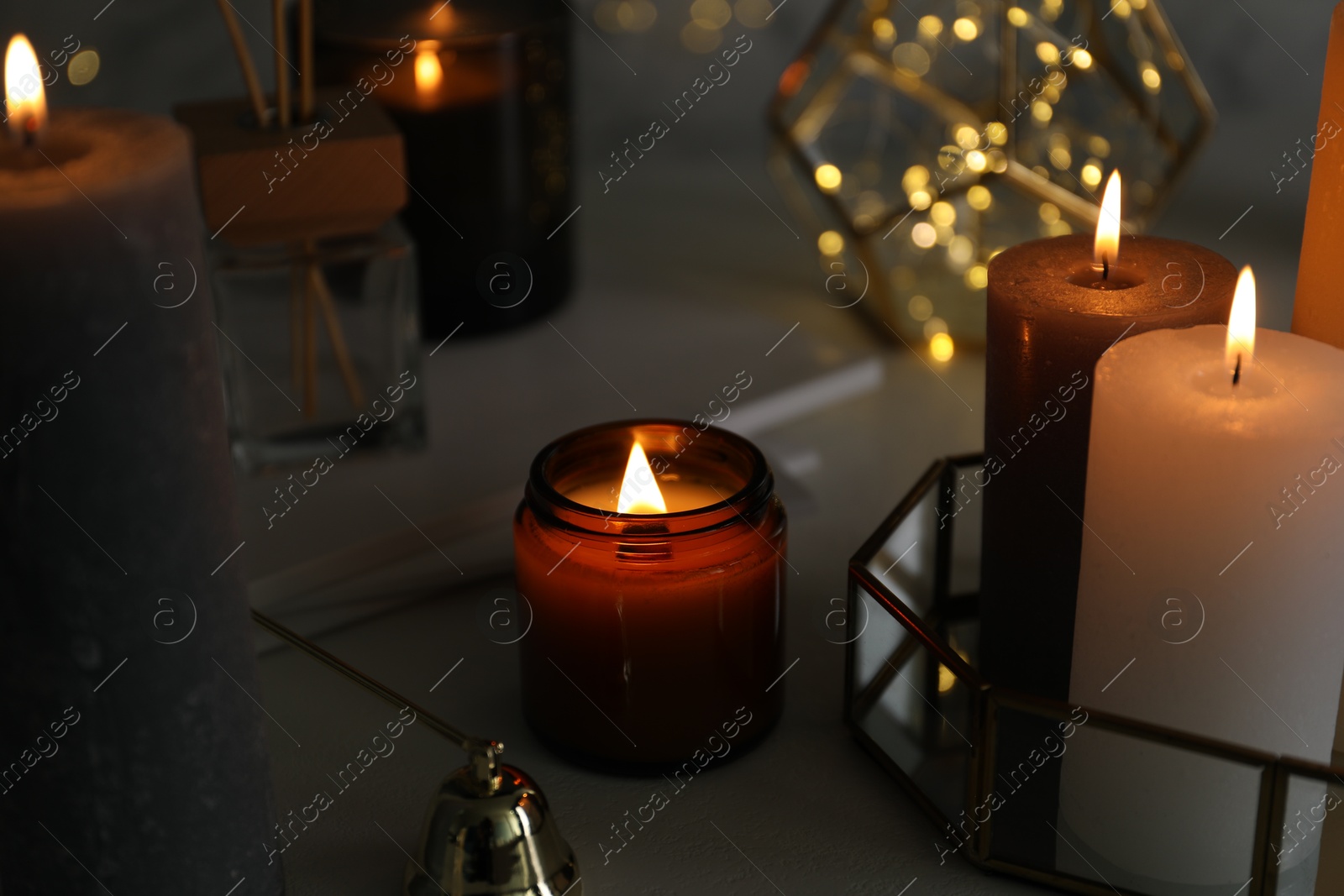 Photo of Beautiful burning candles on table against blurred lights, closeup