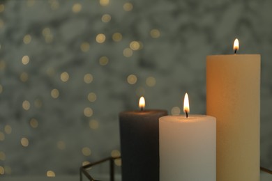 Beautiful burning candles against blurred lights, closeup. Space for text