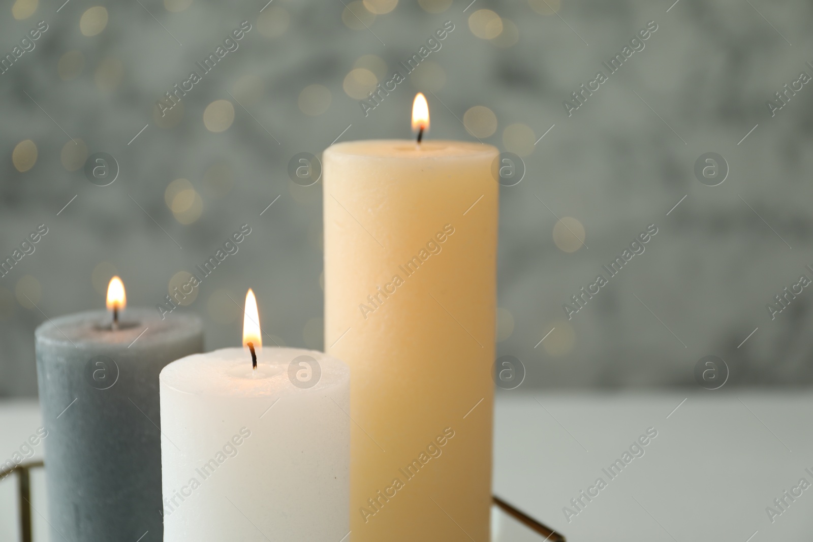 Photo of Beautiful burning candles against blurred lights, closeup. Space for text