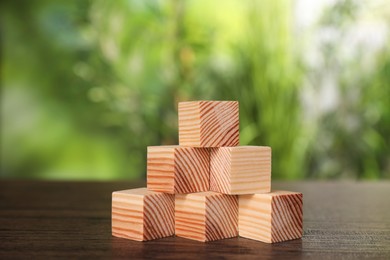 Photo of Many blank wooden cubes on table outdoors