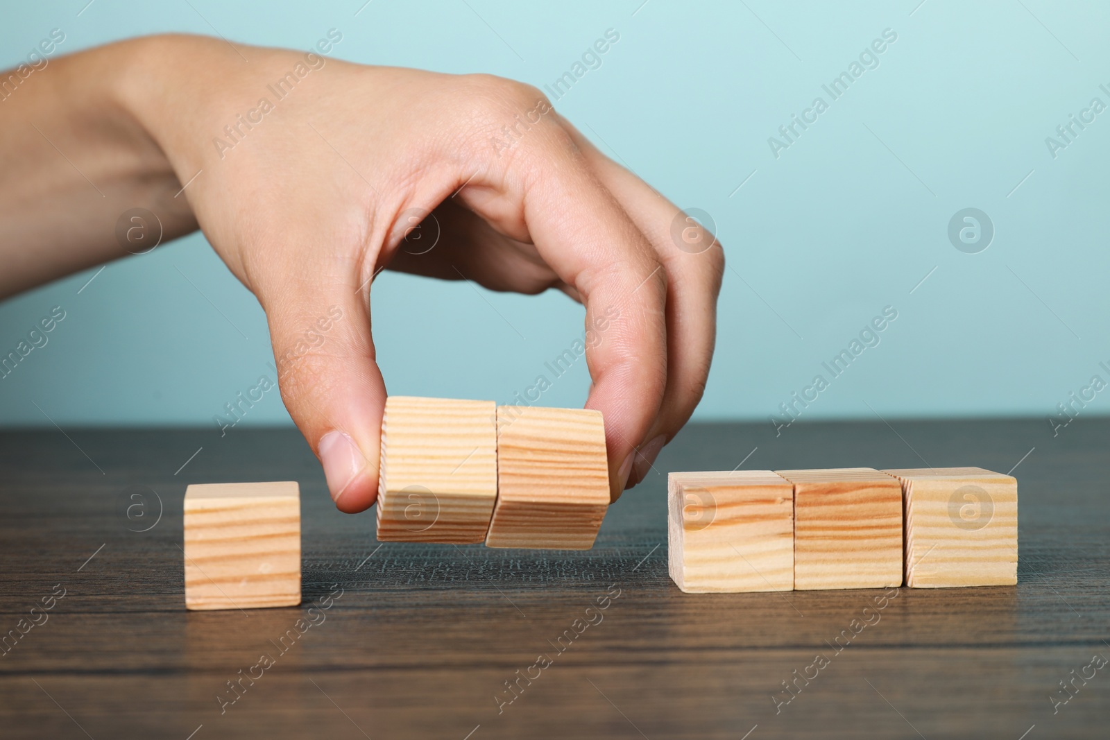 Photo of Woman holding wooden cubes at table, closeup