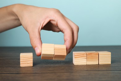 Photo of Woman holding wooden cubes at table, closeup