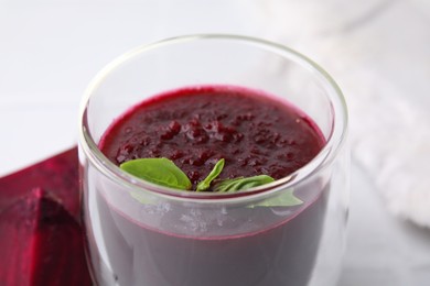 Photo of Fresh beetroot smoothie with mint in glass on white table, closeup. Vegan drink