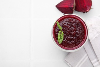 Photo of Fresh beetroot smoothie with mint in glass on white tiled table, top view. Space for text