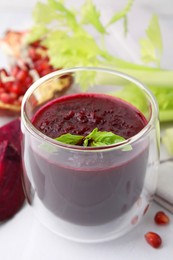 Photo of Fresh beetroot smoothie with mint in glass on white table, closeup