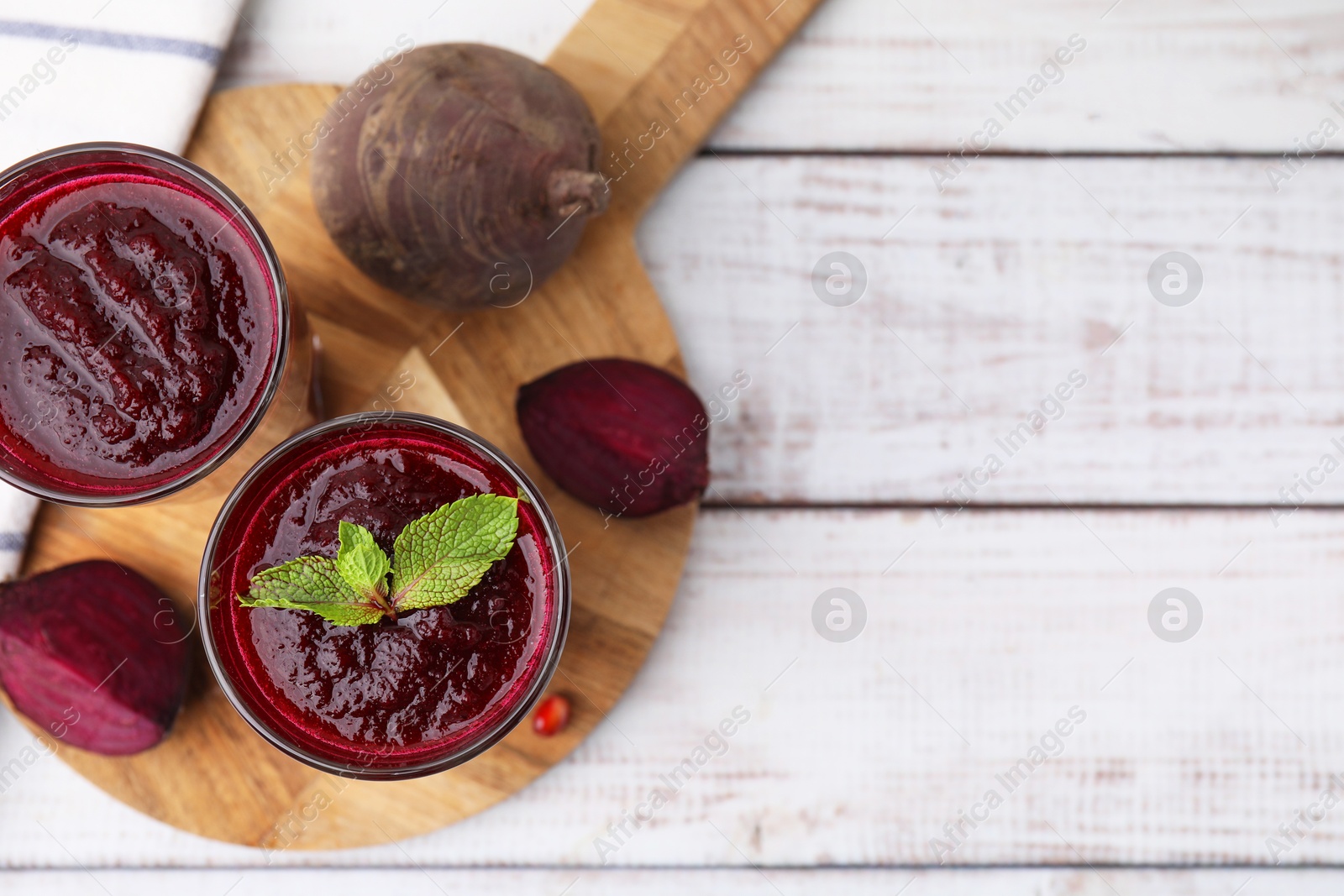 Photo of Fresh beetroot smoothie in glasses on white wooden table, flat lay. Space for text