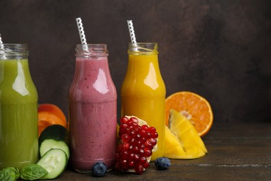 Glass bottles of tasty smoothies and different products on wooden table