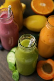 Photo of Glass bottles of tasty smoothies and different products on wooden table, closeup