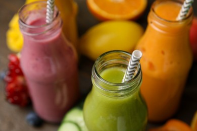 Photo of Glass bottles of tasty smoothies and different products on table, closeup