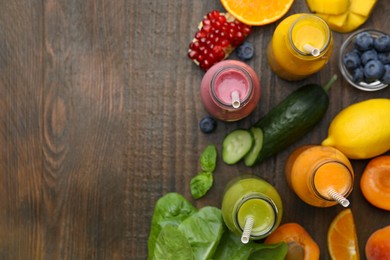 Glass bottles of tasty smoothies and different products on wooden table, flat lay. Space for text