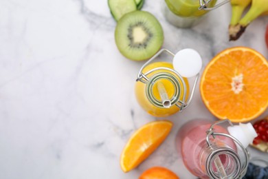 Glass bottles of tasty smoothies and different products on white marble table, flat lay. Space for text