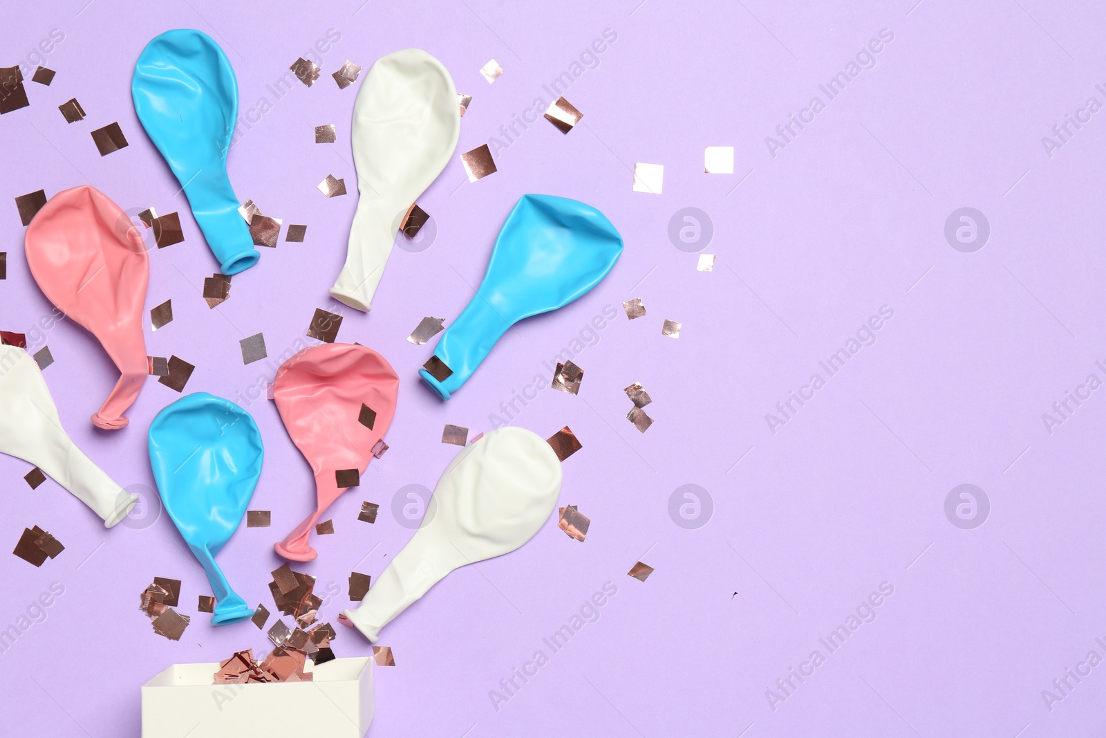 Photo of Shiny confetti and deflated balloons flying out of little box on violet background, flat lay. Space for text