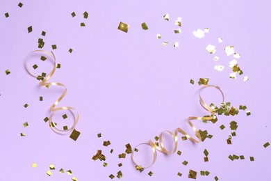 Frame of shiny confetti and streamers on violet background, flat lay. Space for text