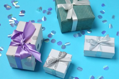 Many different gift boxes and shiny confetti on light blue background