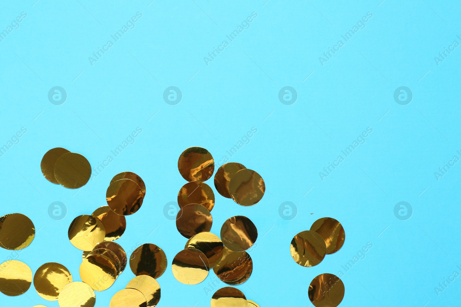 Photo of Shiny confetti on light blue background, top view. Space for text