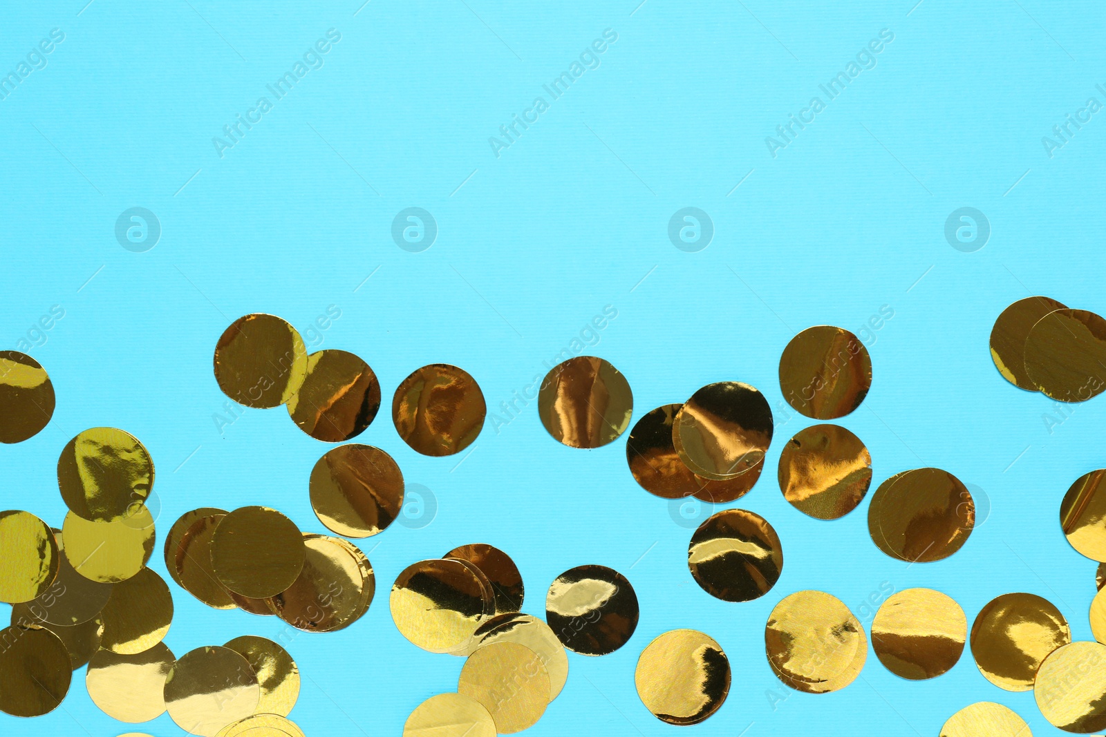 Photo of Shiny confetti on light blue background, top view. Space for text