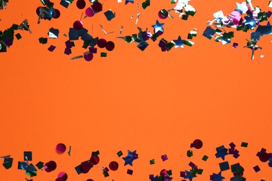 Shiny confetti on orange background, top view. Space for text