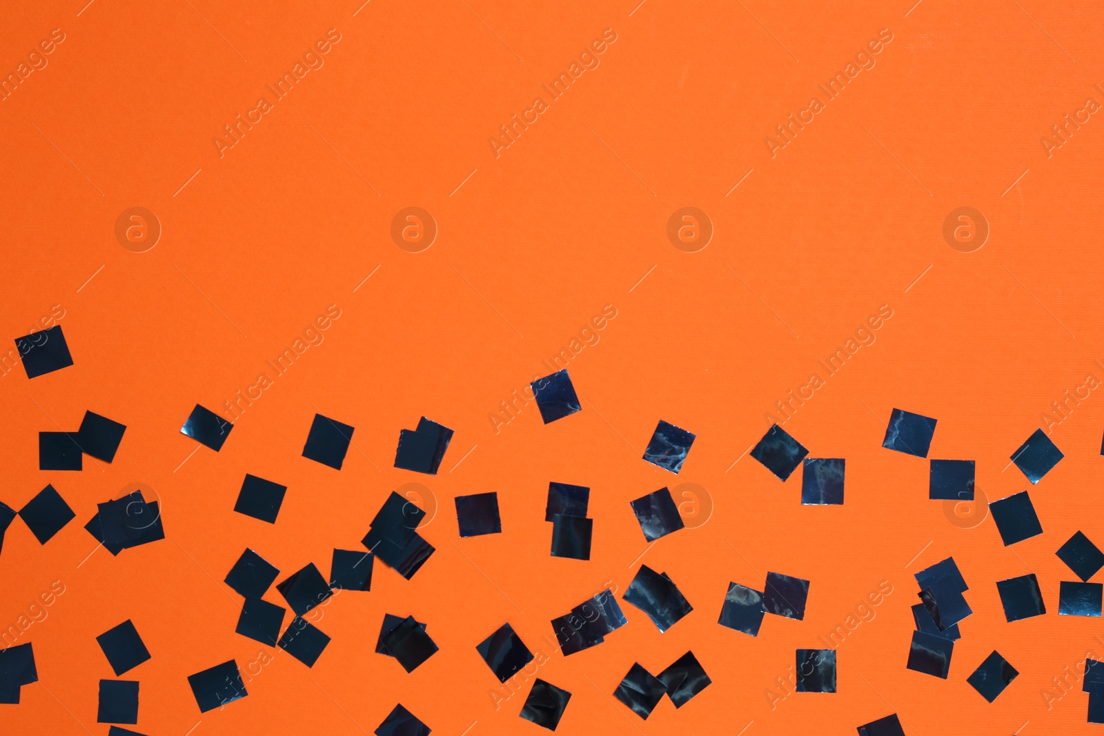 Photo of Shiny confetti on orange background, top view. Space for text