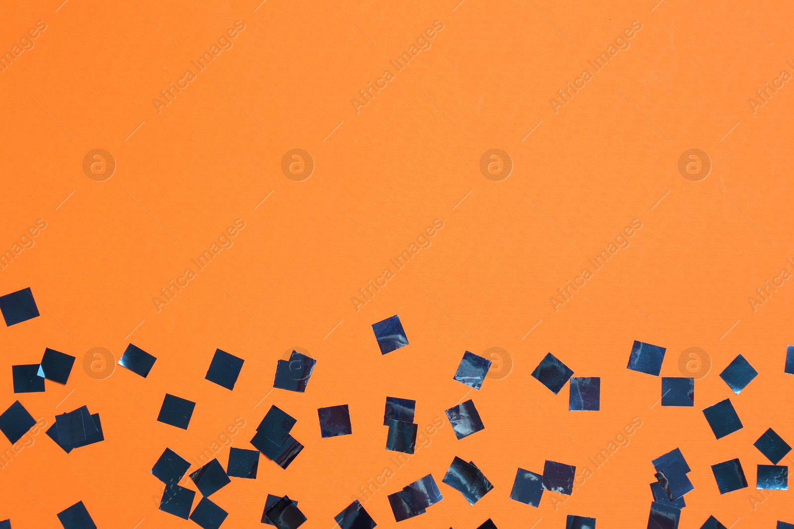 Photo of Shiny confetti on orange background, top view. Space for text