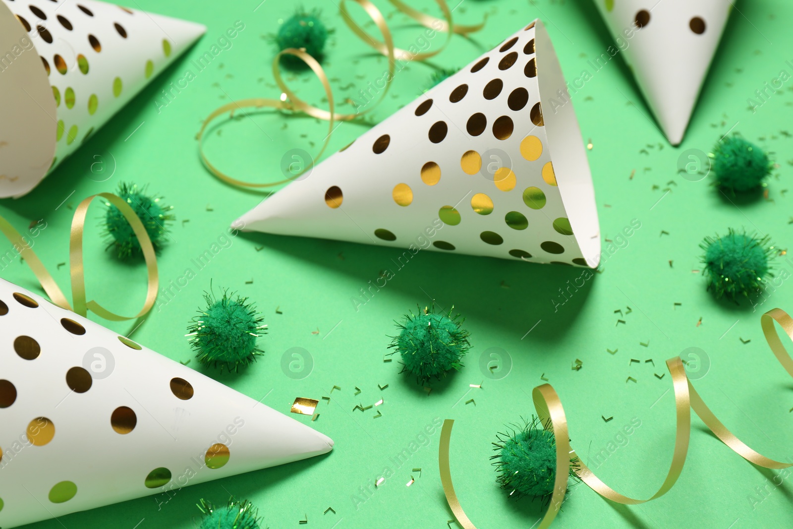 Photo of Festive composition with shiny confetti and party decor on green background, closeup