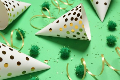 Festive composition with shiny confetti and party decor on green background, closeup