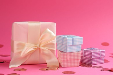 Photo of Beautiful confetti and gift boxes on pink background, closeup