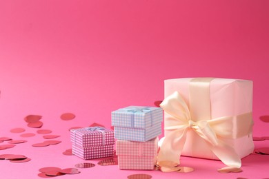 Photo of Beautiful confetti and gift boxes on pink background, closeup. Space for text