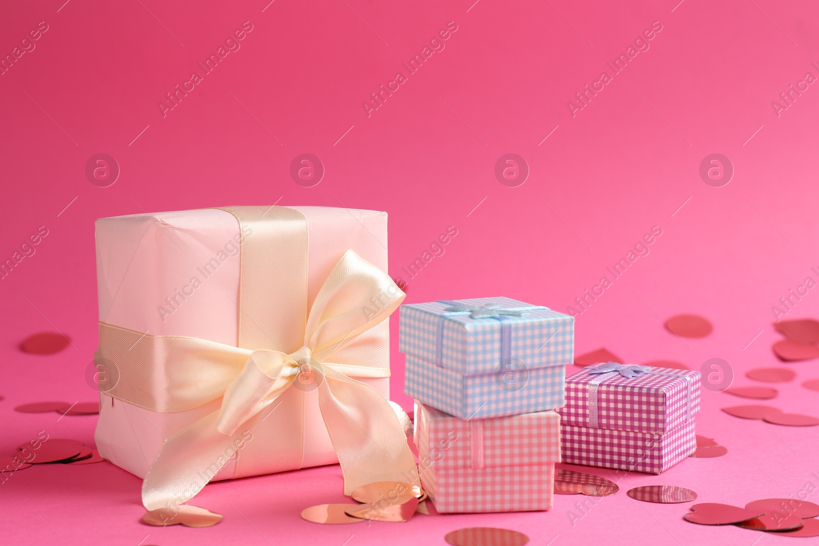 Photo of Beautiful confetti and gift boxes on pink background, closeup