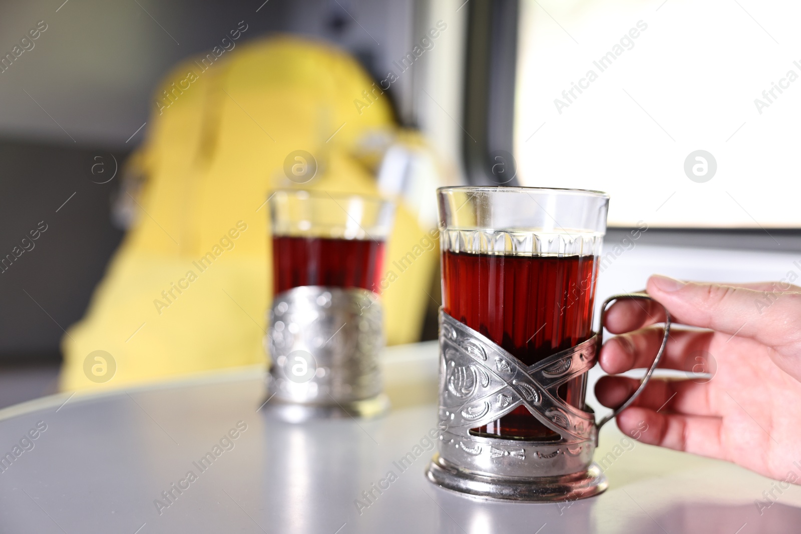 Photo of Young woman with cups of tea at table in train, closeup