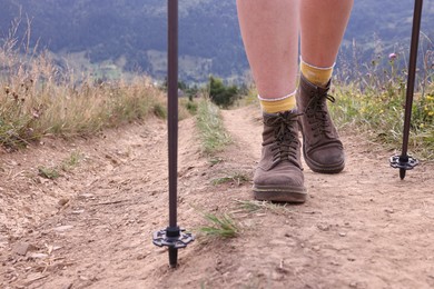 Photo of Young hiker with trekking poles in mountains, closeup