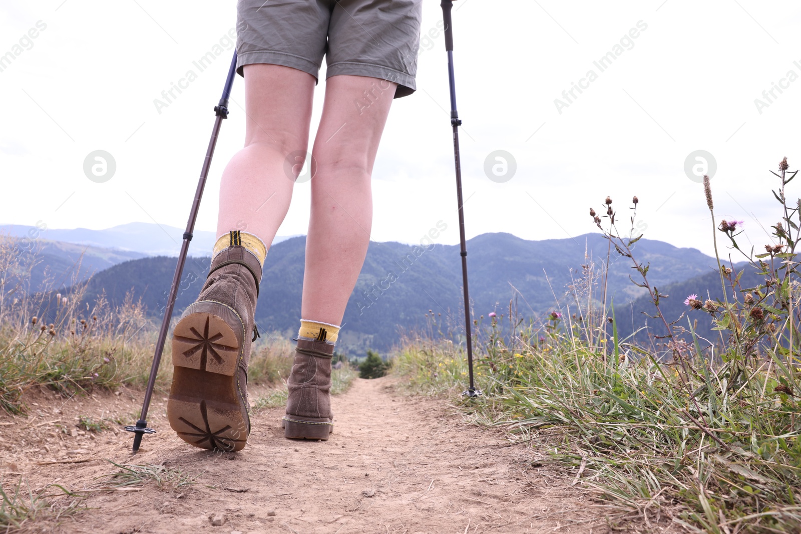 Photo of Young hiker with trekking poles in mountains, closeup