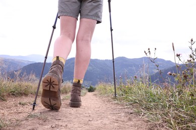 Young hiker with trekking poles in mountains, closeup