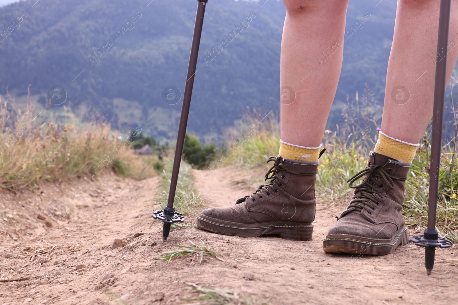 Photo of Young hiker with trekking poles in mountains, closeup