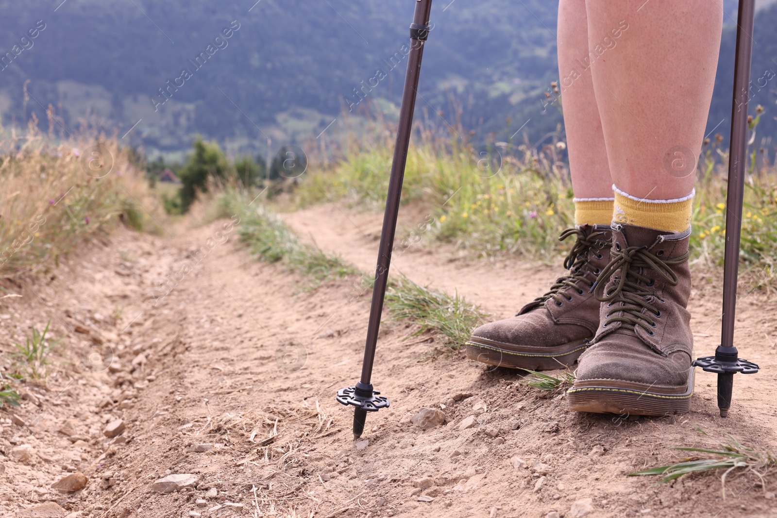 Photo of Young hiker with trekking poles in mountains, closeup. Space for text