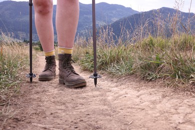 Photo of Young hiker with trekking poles in mountains, closeup. Space for text