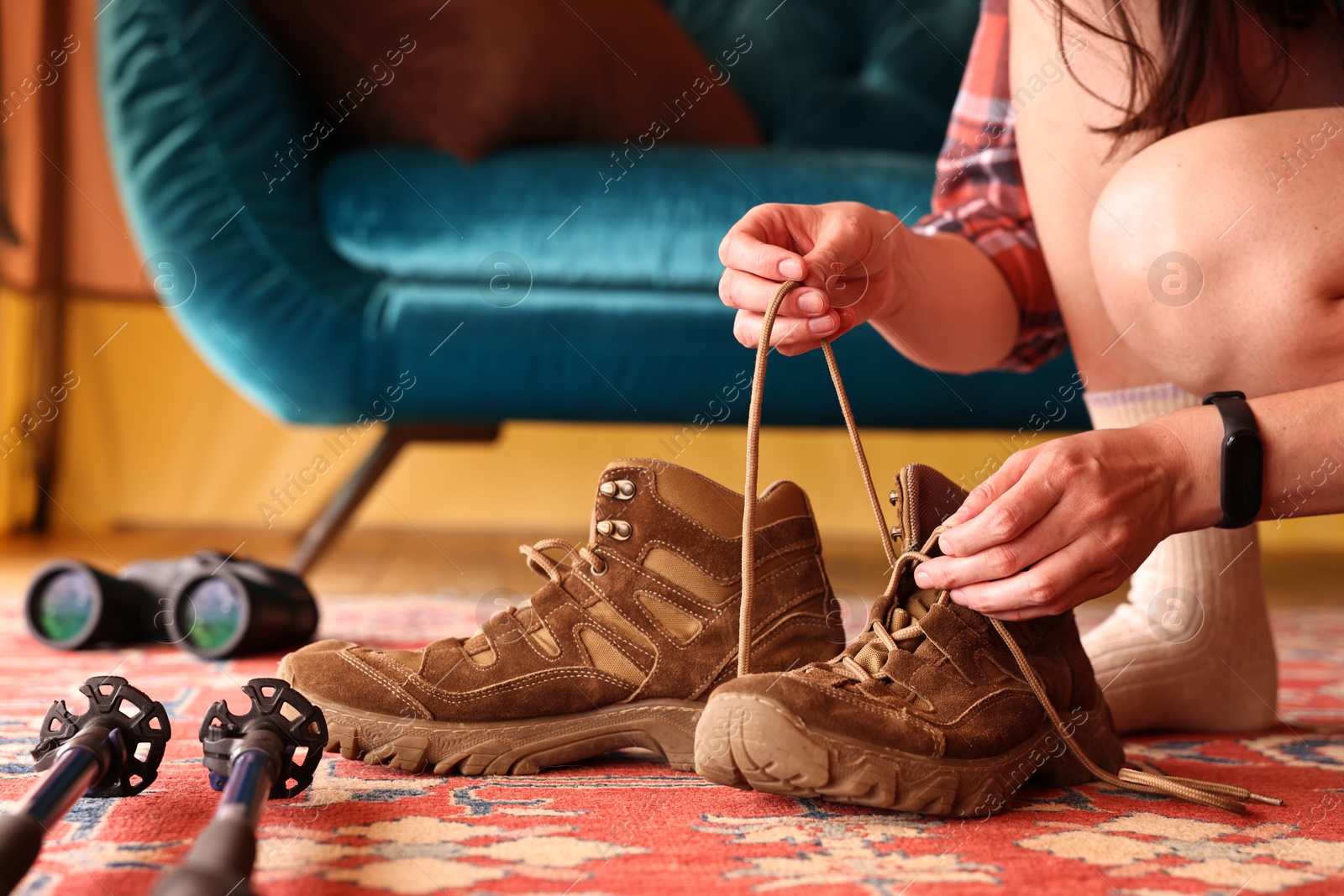 Photo of Young woman tying her trekking shoes indoors, closeup