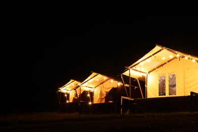 Photo of Tents in mountains at night, space for text. Glamping site