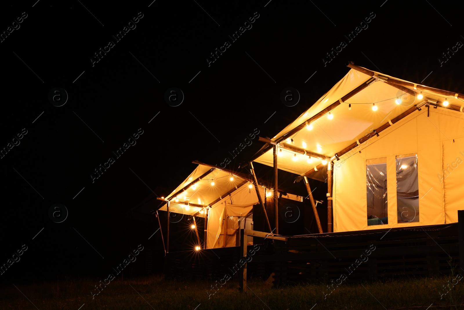 Photo of Tents in mountains at night, space for text. Glamping site