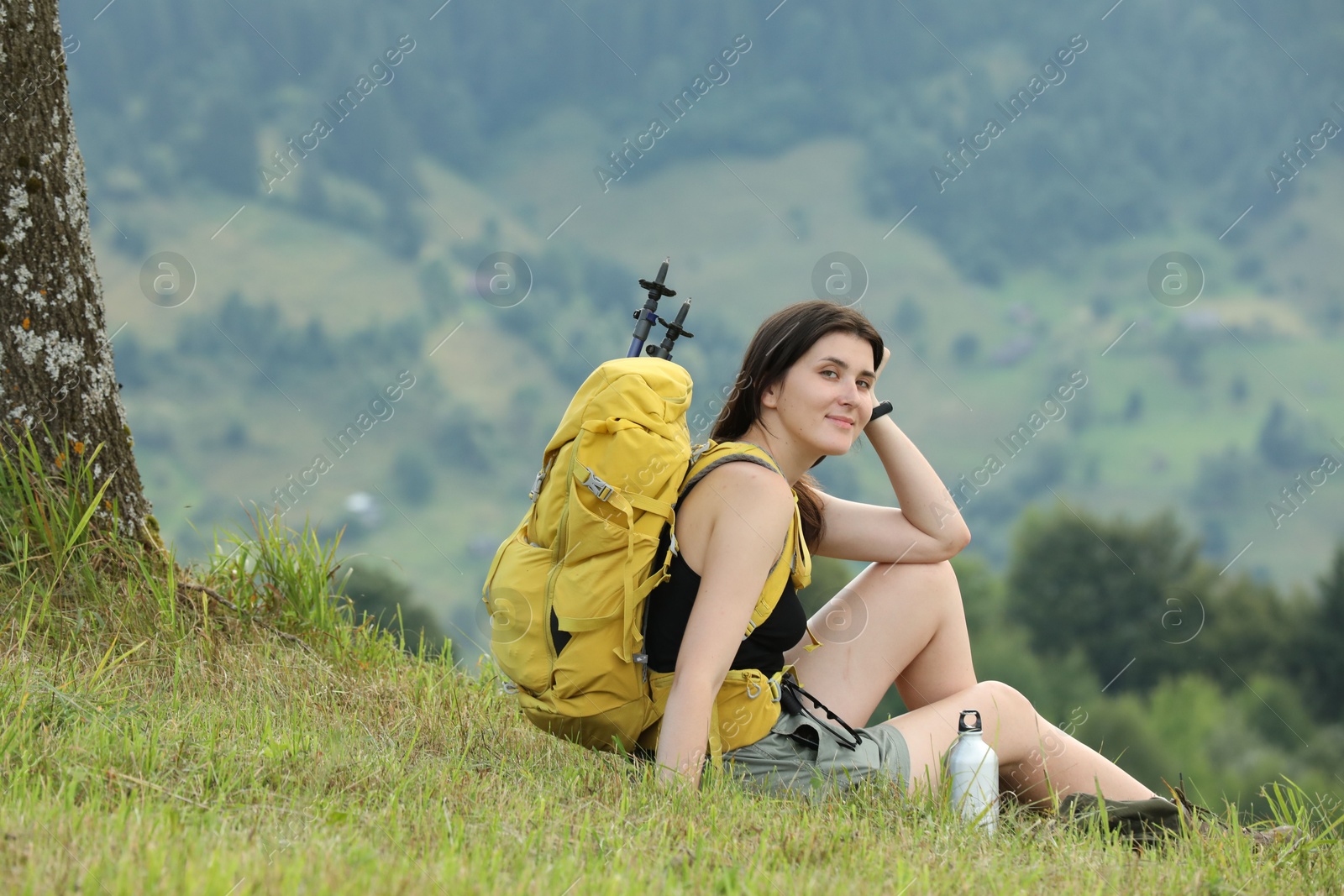 Photo of Young hiker with backpack in mountains, space for text