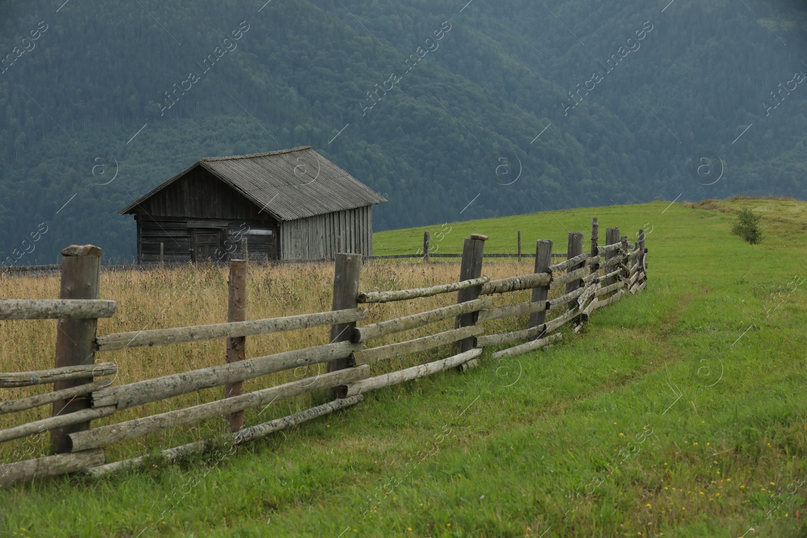 Photo of Beautiful view of building and wooden fence in mountains under sky