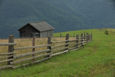 Photo of Beautiful view of building and wooden fence in mountains under sky