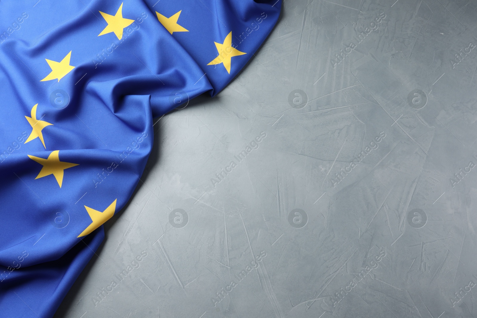 Photo of Flag of European Union on grey table, above view. Space for text