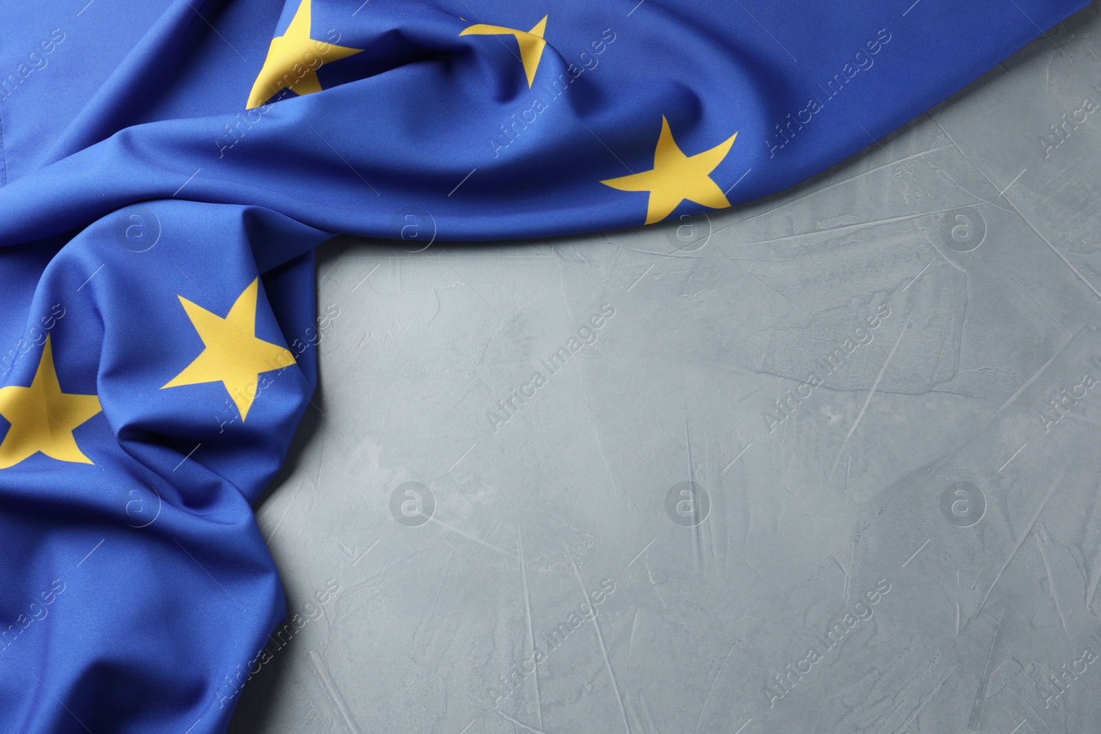 Photo of Flag of European Union on light grey table, above view. Space for text