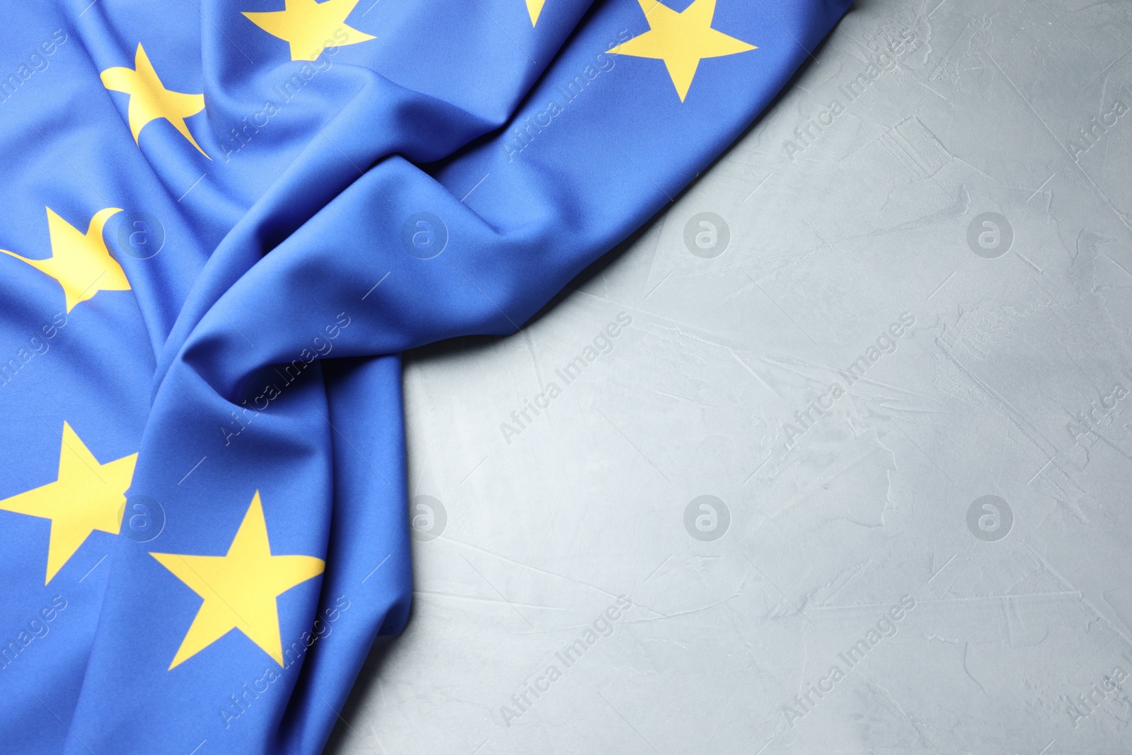 Photo of Flag of European Union on light grey table, top view. Space for text