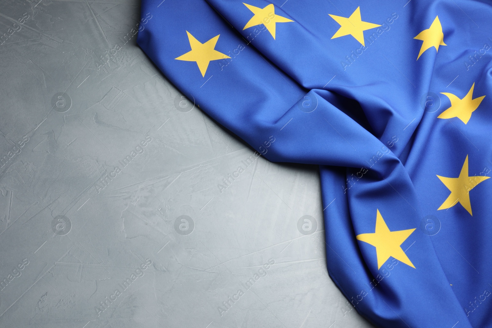 Photo of Flag of European Union on light grey table, above view. Space for text