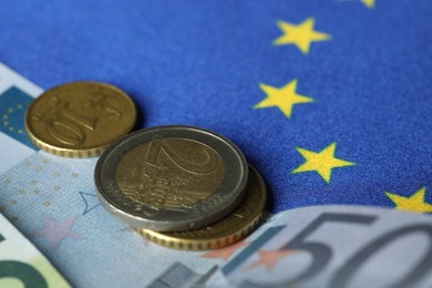 Photo of Euro banknotes and coins on European Union flag, closeup